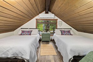 A cozy attic bedroom with two beds, a wooden ceiling, and a window overlooking greenery. - Cabin on Yakima River, Fish, Float, Golf, AC, BBQ (Cle Elum)