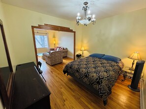 A bedroom with a bed, a chair, a desk, a lamp, and a chandelier. - 2 Bedrooms Apartment & Parking, 15 minutes Downtown (Montréal)