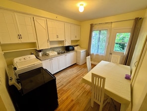 A compact kitchen with white cabinets, a black refrigerator, a microwave, and a washing machine.