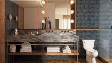 A modern bathroom with a marble countertop, a toilet, and a shelf with towels.