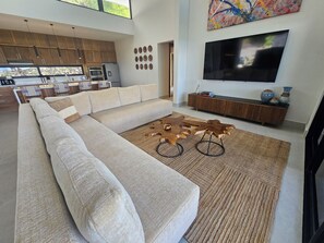 A modern living room with a sectional sofa, a coffee table, and a flat-screen TV.