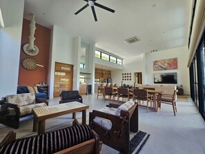 Amplia sala de estar con una mesa de comedor, sofás y una cocina al fondo.