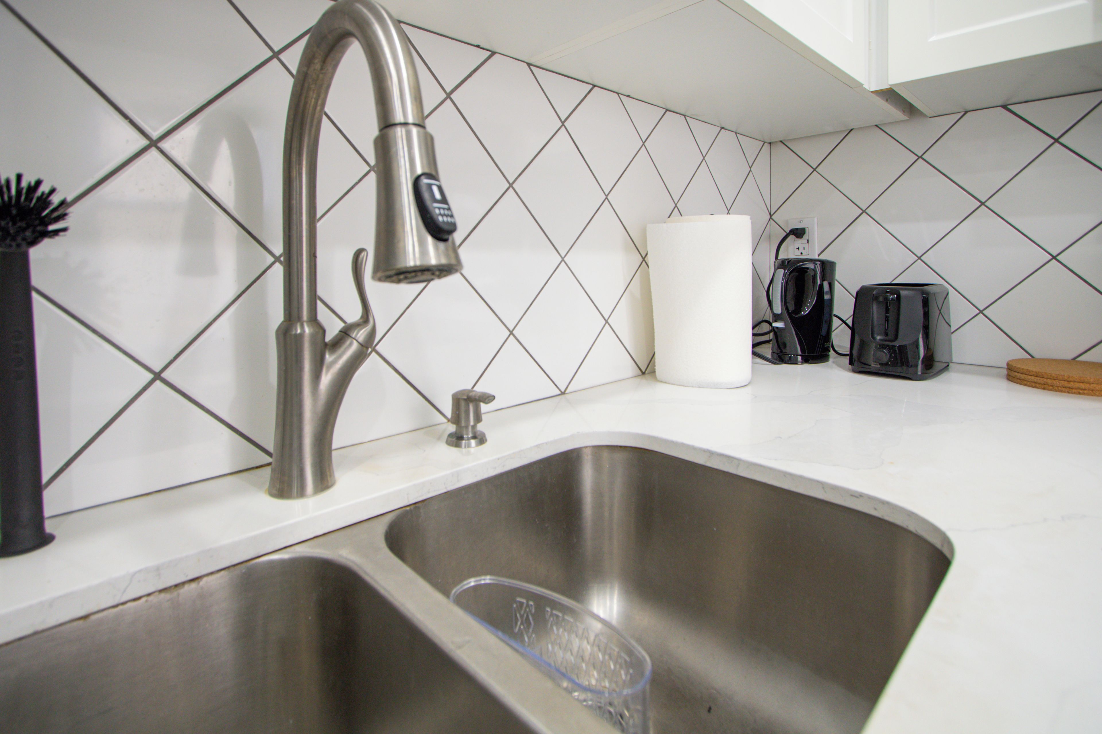 A kitchen with a stainless steel sink, a coffee maker, and a toaster on the countertop.