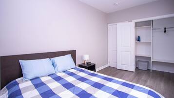 A bedroom with a bed, a nightstand, a lamp, and a wardrobe.