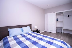 Ein Schlafzimmer mit Bett, Nachttisch, Lampe und Kleiderschrank.