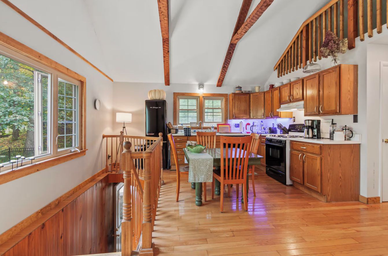 A kitchen with wooden cabinets, a dining table, and a staircase.