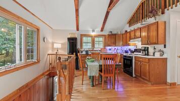 A kitchen with wooden cabinets, a dining table, and a staircase.