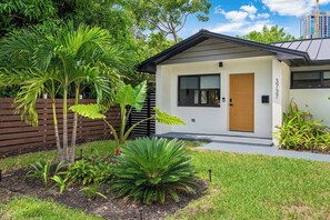 A modern house with a well-maintained garden, a wooden door, and a visible mailbox. - The Cove in the Grove Bungalow in Historic Coconut (Miami)