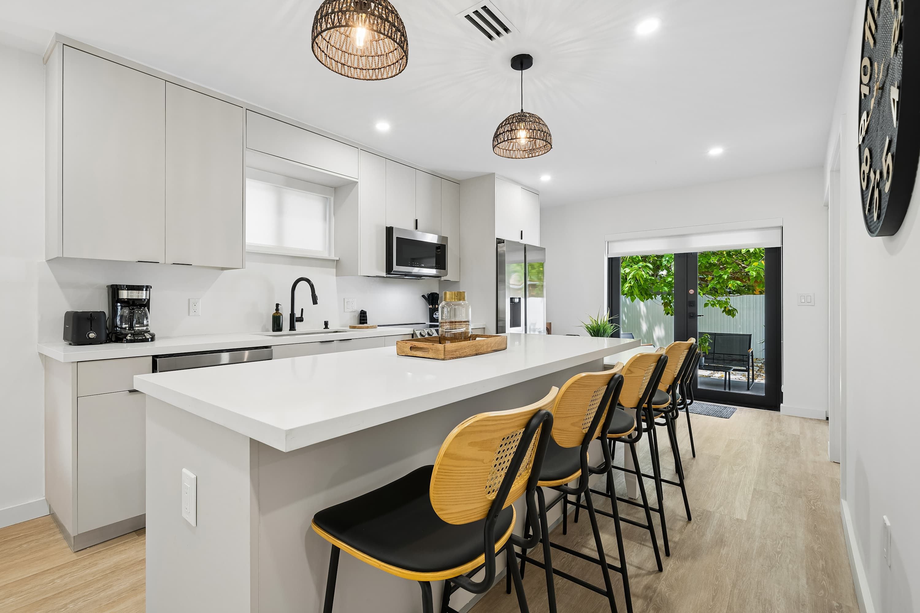 A modern kitchen with white cabinetry, a central island with bar stools, and pendant lighting.