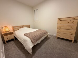 A bedroom with a bed, a nightstand, a dresser, and a wall-mounted light fixture. - Create unforgettable memories in a home designed for comfort, and adventure. (Vernon)