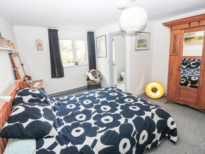 A bedroom with a bed, a chair, a mirror, a wardrobe, and a window. - 11 Church Street (Narberth)