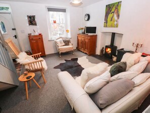 A cozy living room with a sofa, a chair, a television, a fireplace, and a window with a view. - 11 Church Street (Narberth)