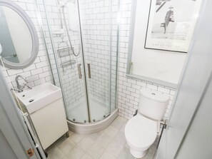 A bathroom with a glass-enclosed shower, a white sink, and a toilet. - 11 Church Street (Narberth)