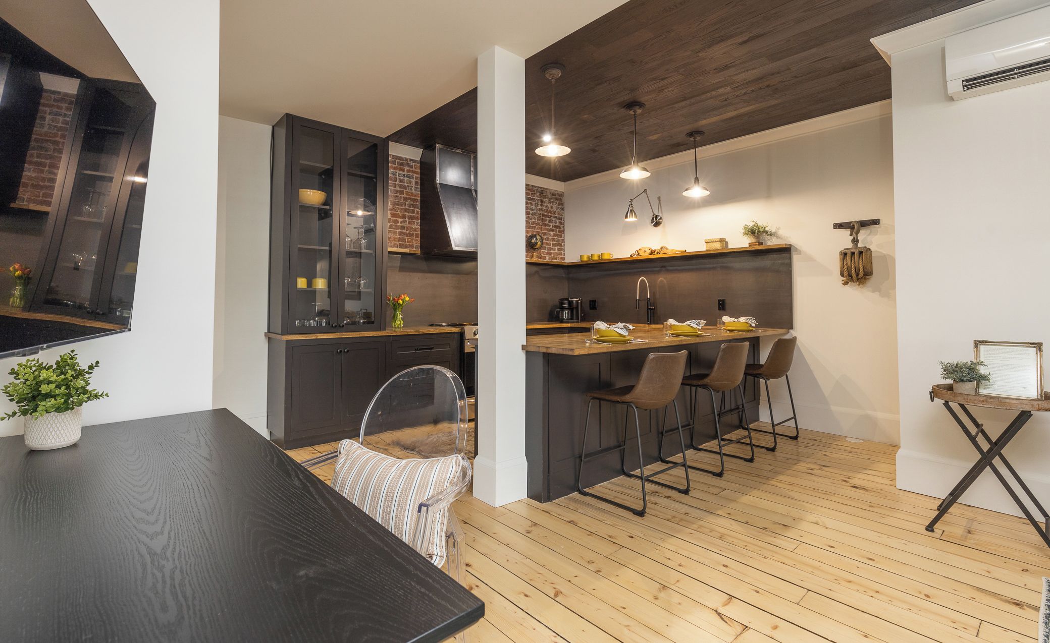 A modern kitchen with a wooden island, bar stools, and a dining table.