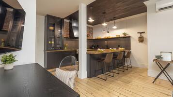 A modern kitchen with a wooden island, bar stools, and a dining table.