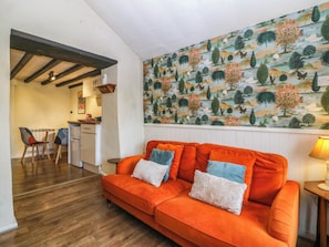 Ein Wohnzimmer mit einer Couch, eine Essecke mit Stühlen, eine Küche und ein großes Wandbild.