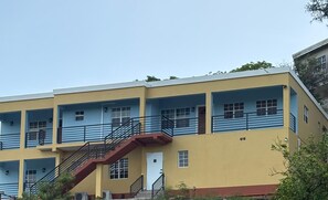 A multi-story building with a flat roof, a central staircase, and a series of windows on each floor. - Manna Heights. Perfect 2-bedroom apartment with AC in peaceful Bolands. (Bolands)
