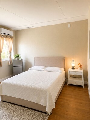 A bedroom with a bed, bedside tables, a nightstand, a window with curtains, and an air conditioning unit. - Peaceful 1-bedroom studio with AC, pool front and free parking, in vibrant Miami (Miami)