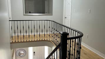 Una escalera con barandilla negra, peldaños de madera y una puerta blanca al final.