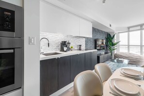 A modern kitchen with dark cabinets, a white countertop, and a built-in oven. - Waterfront 2BR Suite, Luxury Views & Parking | Parking Available (Toronto)