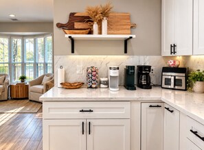 A modern kitchen with white cabinetry, a marble countertop, and various appliances including a coffee maker and a toaster. - Perfect Conroe 4BR Retreat Private Pool  9 Beds (Conroe)