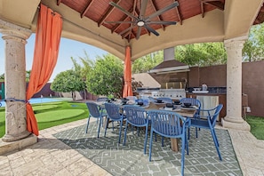Eine Terrassengruppe im Freien mit Grill, blauen Stühlen und einem Essplatz.