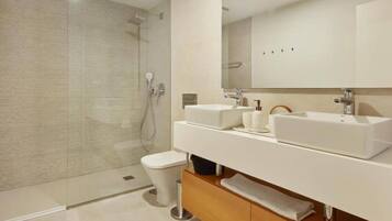 A modern bathroom with a glass-enclosed shower, a double sink vanity, and a toilet.