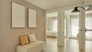 A modern living room with a sofa, a ceiling light, and a door leading to another room.