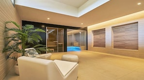 Un interior moderno con una zona de estar, un vidrio que da a un spa y una pared de madera con estantes integrados.