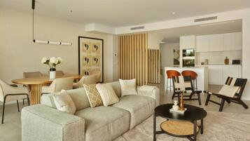 A modern living room with a sofa, a dining table, and a kitchen area in the background.