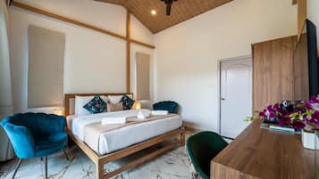 A bedroom with a bed, two chairs, a desk, and a ceiling fan.