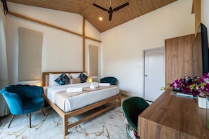 Ein Schlafzimmer mit einem Bett, zwei Stühlen, einem Schreibtisch und einem Deckenventilator.