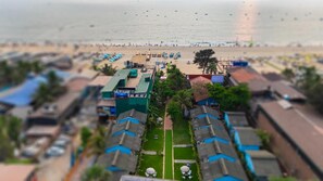 Un hôtel situé sur la côte, composé de plusieurs bâtiments à étages, avec une plage et un port de plaisance.