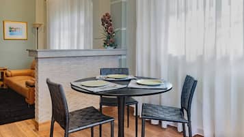 Un espace repas comprenant une table ronde, quatre chaises et une cloison en briques blanches.