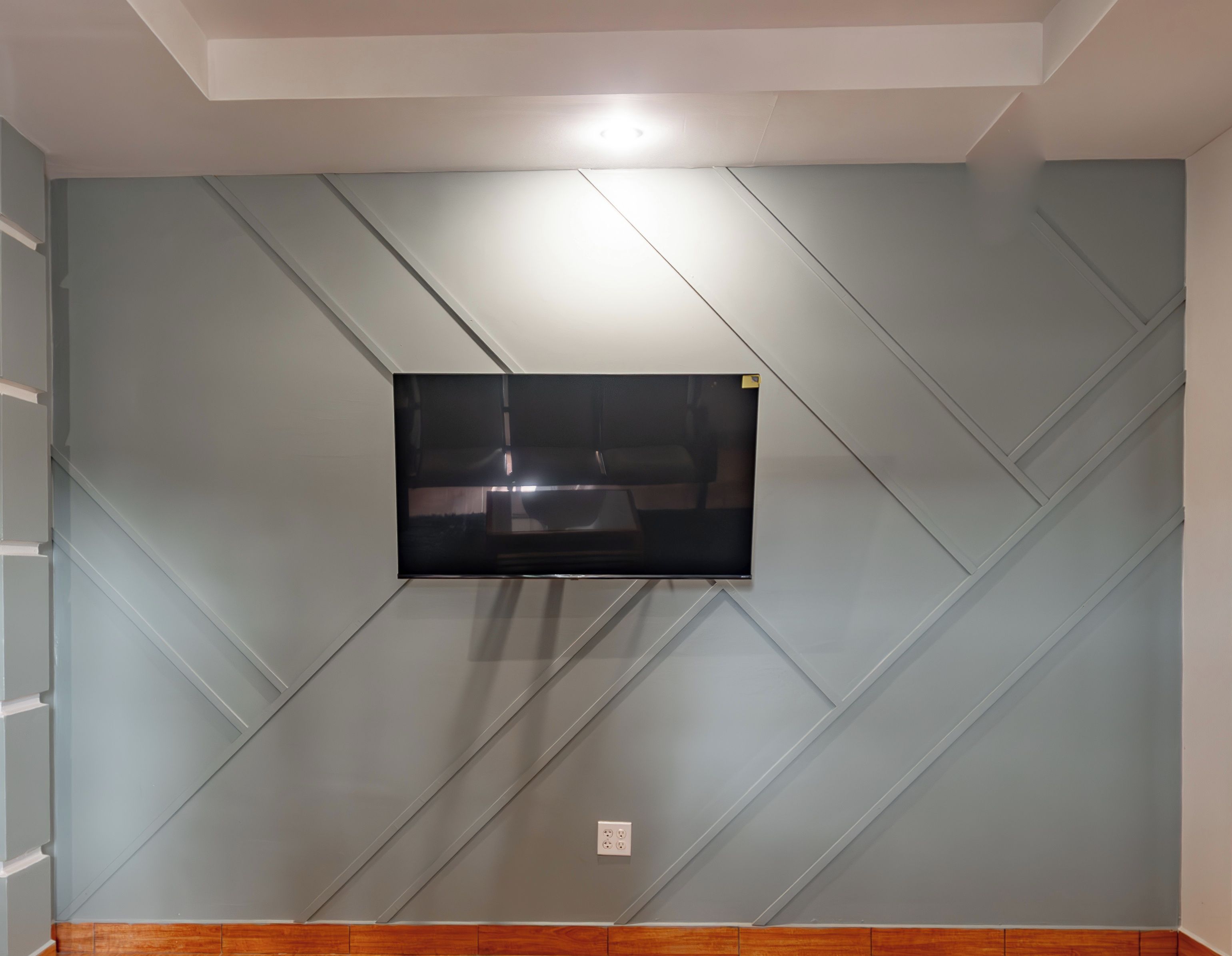 A wall-mounted television in a room with a geometric patterned wall design.