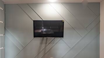 A wall-mounted television in a room with a geometric patterned wall design.
