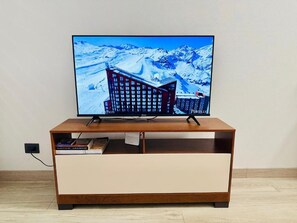 A television on a wooden TV stand with a snowy mountain backdrop.