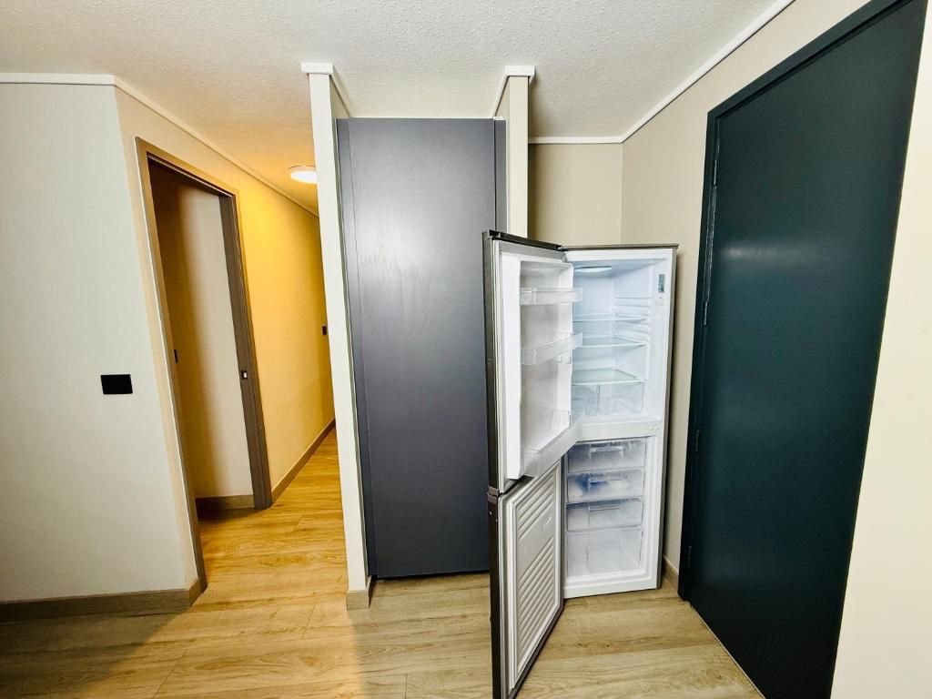 A hallway with a refrigerator, a door, and a wall.