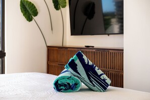 A neatly made bed with a folded blanket, a wooden headboard, and a wall-mounted television. - [New] Modern Luxe 2 Bedroom Condo in Waikiki with Diamond Head Views! (Honolulu)