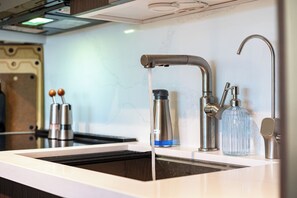 Una cocina moderna con un lavamanos de acero inoxidable, un grifo y una botella de agua.