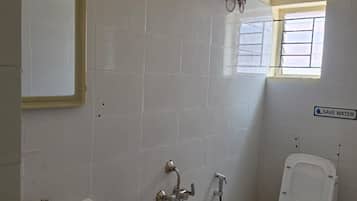 Un baño con lavamanos, inodoro, ducha y un balde.