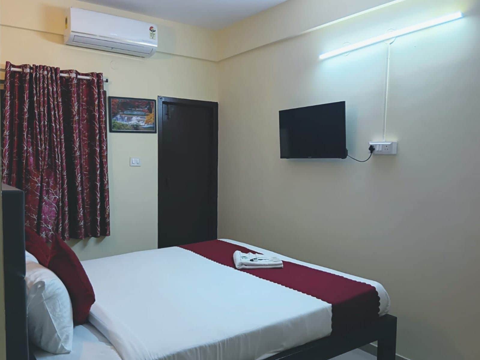Habitación de hotel con cama, televisor de pantalla plana en la pared y aire acondicionado.