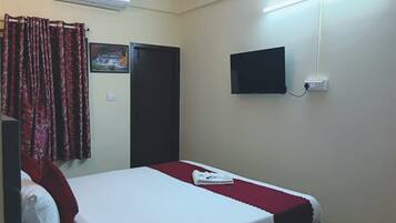 Habitación de hotel con cama, televisor de pantalla plana en la pared y aire acondicionado.