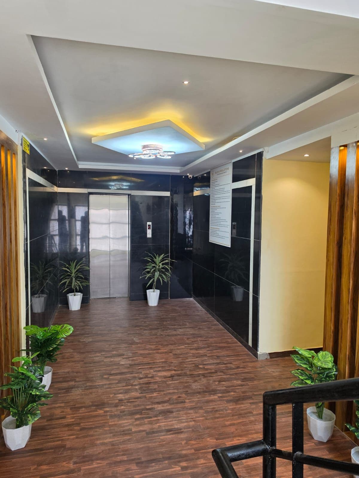 Un interior moderno con suelo de madera, plantas en macetas e iluminación empotrada en el techo.