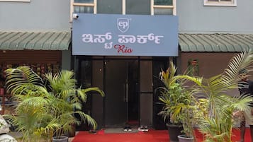 Entrada de hotel con alfombra roja, plantas en macetas y un letrero que dice 'Rio'.