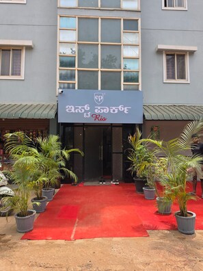 Entrada de hotel con alfombra roja, plantas en macetas y un letrero que dice 'Rio'.