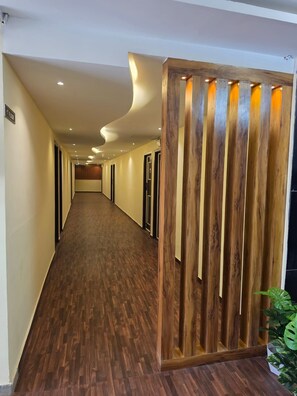 Pasillo de hotel con paneles de madera y una planta a la derecha.