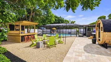 Un espace extérieur aménagé avec une terrasse, une piscine, des sièges et une structure en bois.