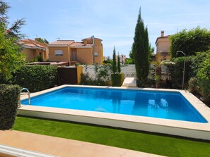 A rectangular swimming pool with a white edge, surrounded by a well-maintained lawn and various greenery. - Villa San Antonio with a private pool (Peníscola)