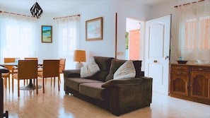 A living room with a sofa, chairs, a dining table, and a kitchen area. - Villa San Antonio with a private pool (Peníscola)